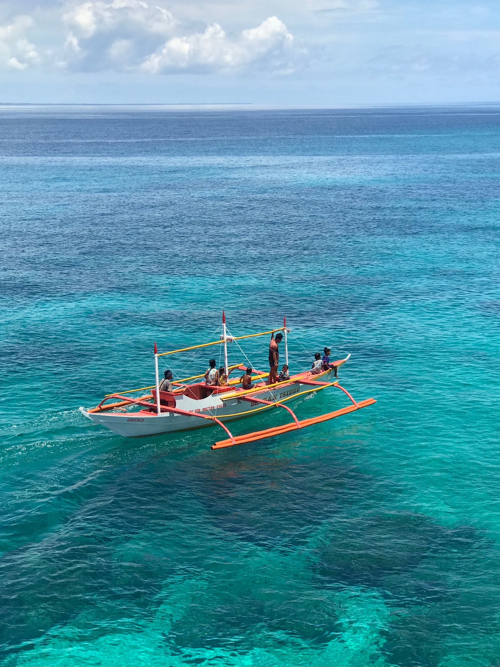Perahu bercadik di laut biru jernih